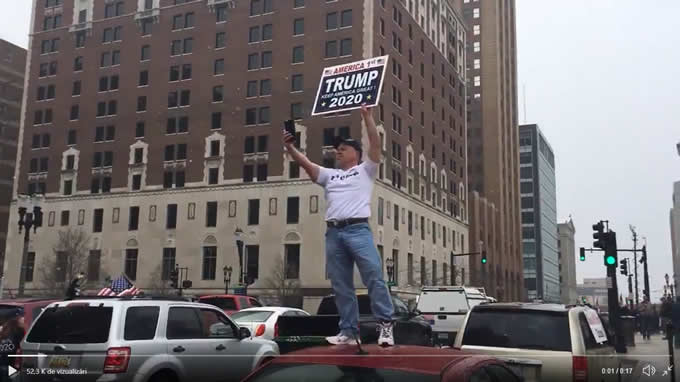 Protestatar ținând o pancartă pe care scrie Trump 2020: Keep America great again.